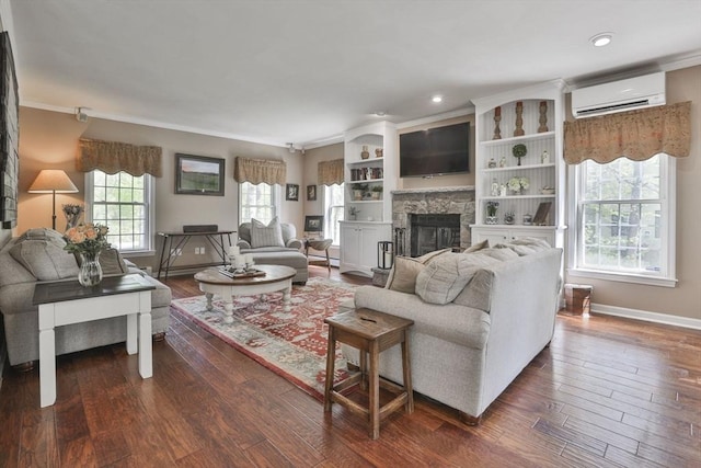 living area with a wall unit AC, ornamental molding, dark wood finished floors, baseboards, and a stone fireplace
