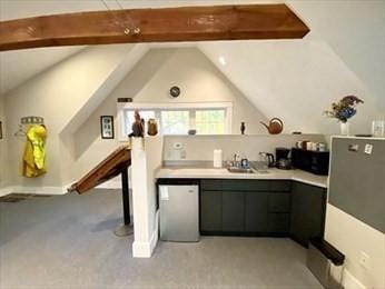 kitchen featuring dishwasher, lofted ceiling with beams, light colored carpet, and sink