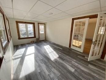 spare room with french doors, a drop ceiling, and dark wood-type flooring