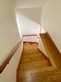 stairs with hardwood / wood-style flooring and a baseboard heating unit