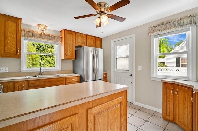 kitchen with freestanding refrigerator, a sink, light countertops, and plenty of natural light