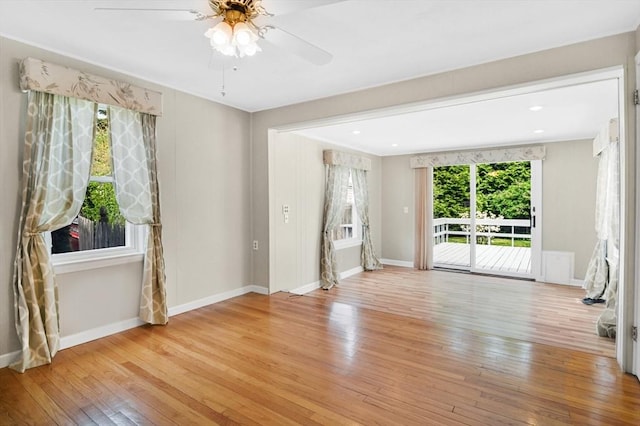 spare room with light wood-style floors, a ceiling fan, and baseboards