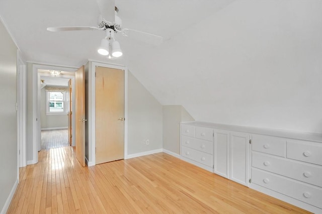 additional living space featuring light wood-style flooring, baseboards, a ceiling fan, and vaulted ceiling