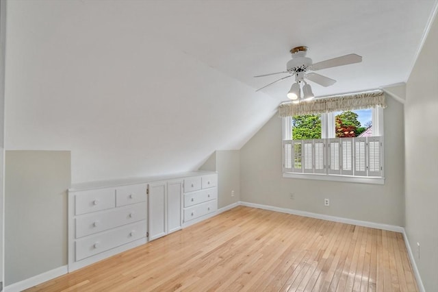 additional living space with light wood finished floors, baseboards, ceiling fan, and vaulted ceiling