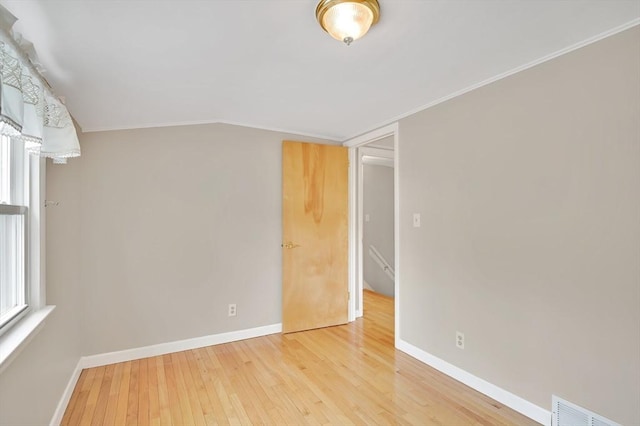 spare room with hardwood / wood-style floors, baseboards, vaulted ceiling, and crown molding
