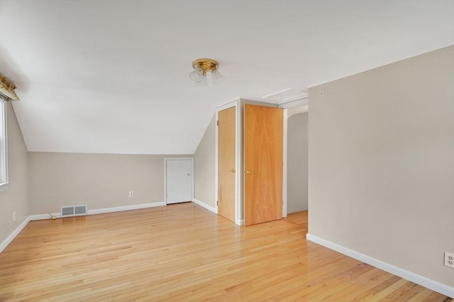 additional living space with light wood-style floors, lofted ceiling, and baseboards