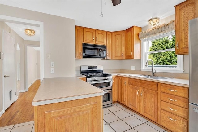 kitchen with black microwave, double oven range, a sink, light countertops, and light tile patterned floors