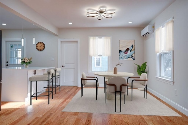 dining room featuring light wood-type flooring, an AC wall unit, and a wealth of natural light