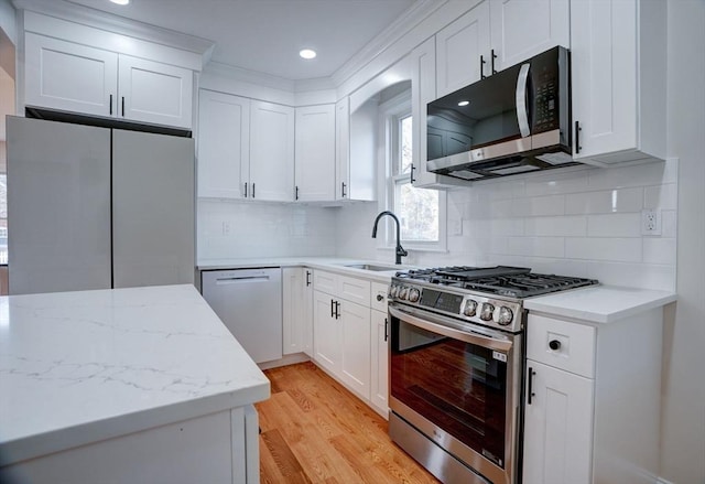 kitchen with tasteful backsplash, white cabinetry, sink, and appliances with stainless steel finishes