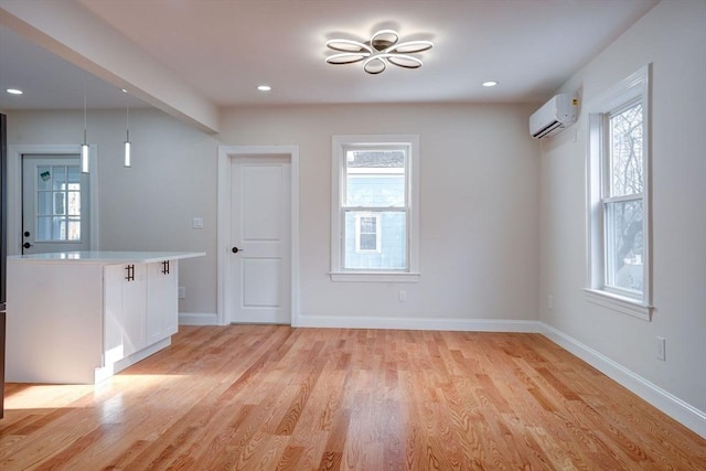 unfurnished room featuring light wood-type flooring, a wall unit AC, and a healthy amount of sunlight