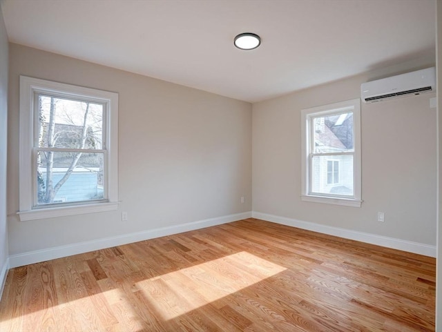 unfurnished room with a wall mounted AC and light hardwood / wood-style floors