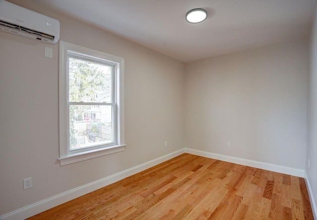 spare room featuring a wall unit AC and light hardwood / wood-style floors