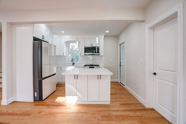 kitchen with backsplash, refrigerator, white cabinets, and hanging light fixtures