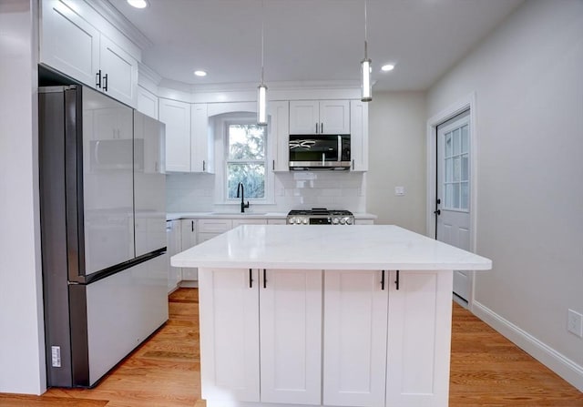 kitchen with decorative light fixtures, a kitchen island, sink, and stainless steel appliances