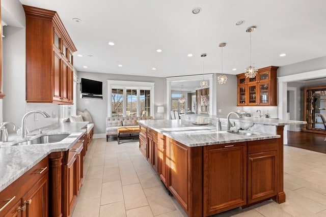 kitchen with light stone counters, brown cabinets, and a sink