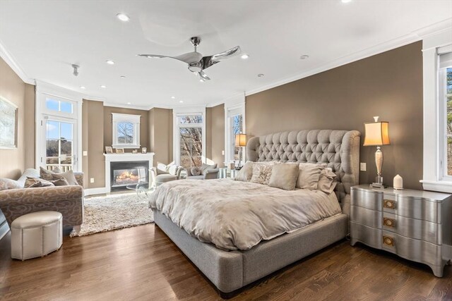 bedroom with a glass covered fireplace, crown molding, access to exterior, and dark wood-style floors