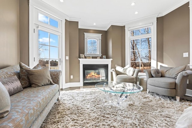 living room featuring recessed lighting, baseboards, a glass covered fireplace, and crown molding