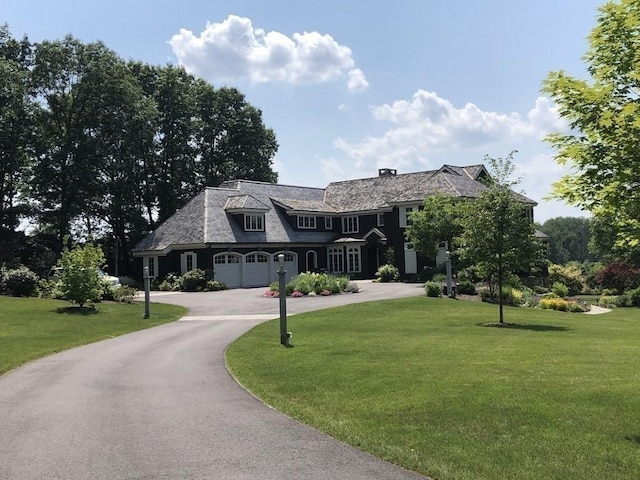 view of front of property featuring a front lawn and curved driveway