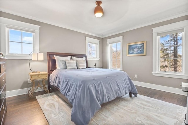 bedroom with crown molding, wood finished floors, and baseboards