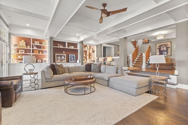 living room featuring built in shelves, ceiling fan, stairway, beamed ceiling, and wood finished floors