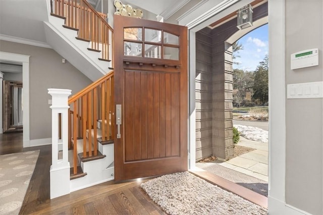 entryway featuring stairs, baseboards, wood finished floors, and crown molding