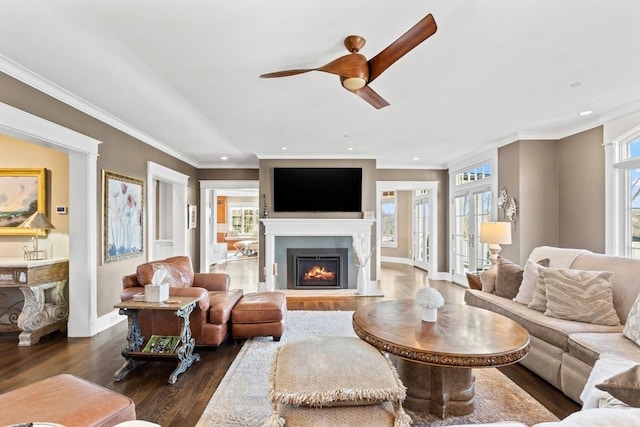 living area with wood finished floors, baseboards, a lit fireplace, french doors, and crown molding