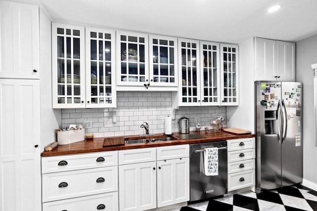 kitchen featuring glass insert cabinets, white cabinetry, butcher block counters, and appliances with stainless steel finishes