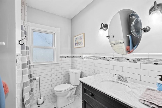 bathroom featuring toilet, a wainscoted wall, tile walls, and vanity