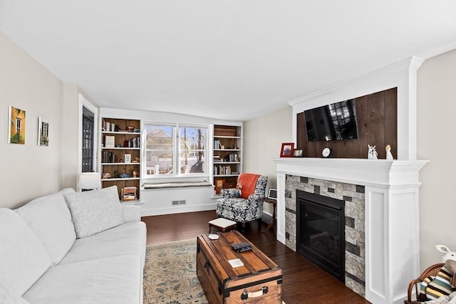 living room with a stone fireplace, wood finished floors, visible vents, and baseboards