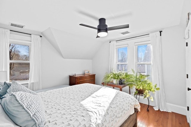 bedroom featuring vaulted ceiling, wood finished floors, visible vents, and baseboards