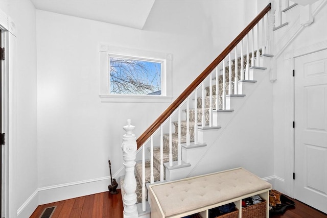 staircase featuring wood finished floors, visible vents, and baseboards