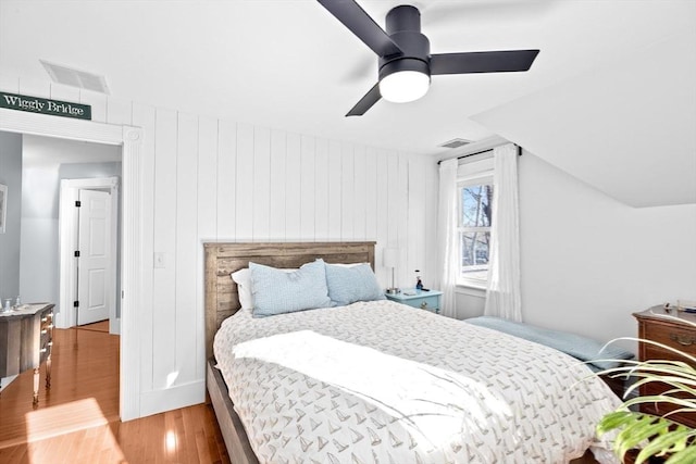 bedroom featuring lofted ceiling, wood finished floors, visible vents, and a ceiling fan