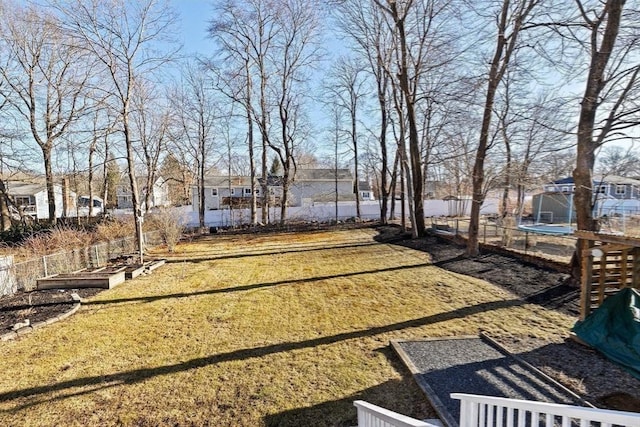 view of yard with a trampoline, a residential view, and fence