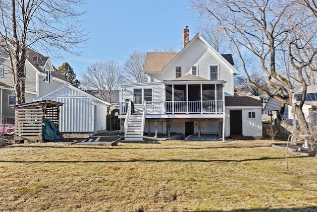 back of property featuring a chimney, stairway, a sunroom, a shed, and an outdoor structure