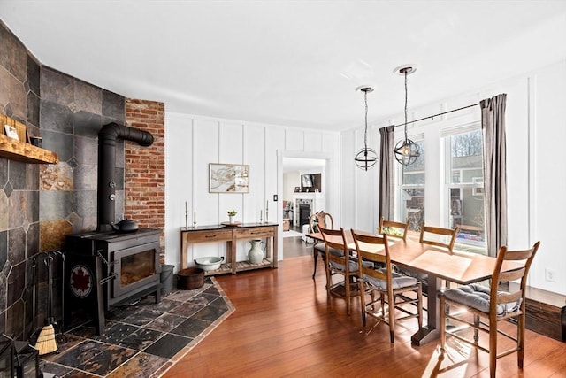 dining space with a wood stove, a fireplace, wood-type flooring, and a decorative wall