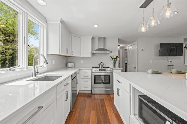 kitchen featuring stainless steel appliances, wall chimney exhaust hood, a sink, white cabinets, and dark wood-style floors
