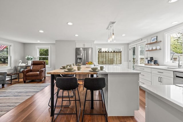 kitchen with stainless steel appliances, a sink, light countertops, white cabinetry, and a breakfast bar