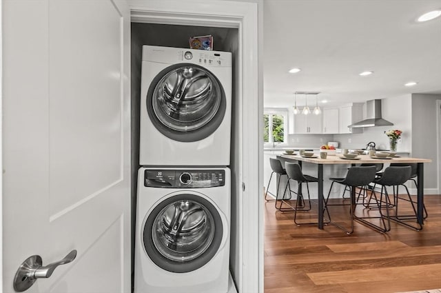 washroom featuring stacked washer and clothes dryer, wood finished floors, and recessed lighting