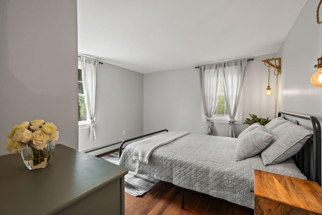 bedroom with wood finished floors and a baseboard heating unit