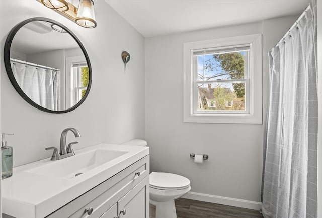 full bathroom with wood finished floors, plenty of natural light, baseboards, and toilet
