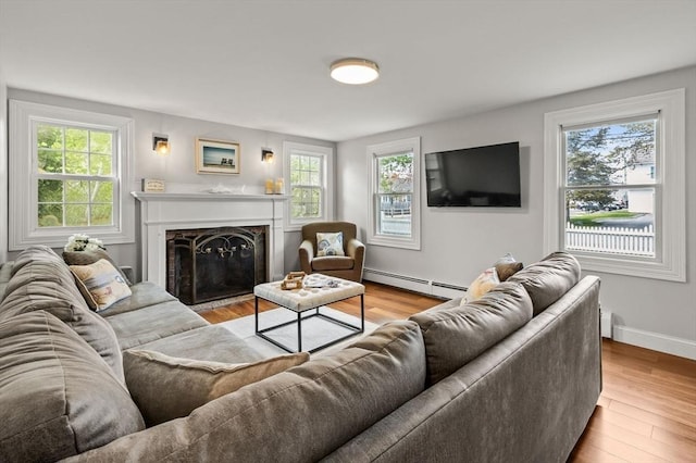 living area featuring a baseboard radiator, healthy amount of natural light, and wood finished floors