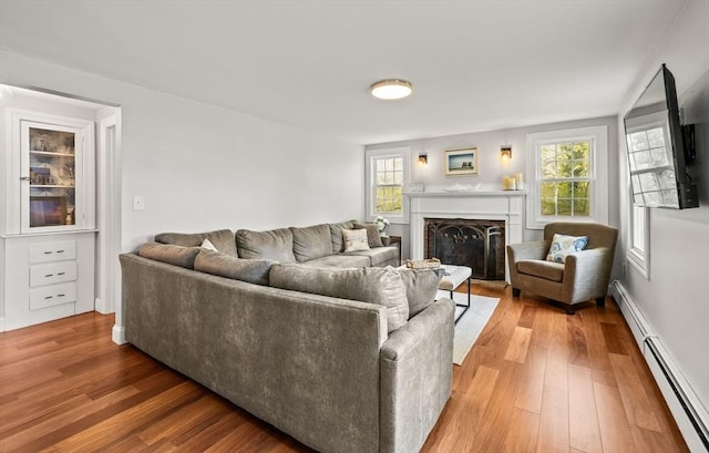 living area with a baseboard radiator, light wood-style floors, and a fireplace