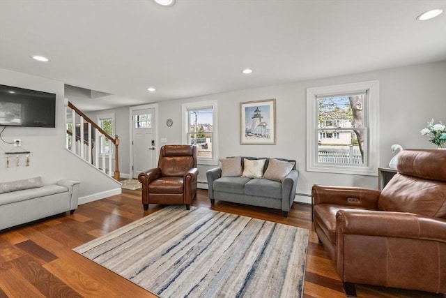 living area with stairway, wood finished floors, recessed lighting, baseboard heating, and healthy amount of natural light
