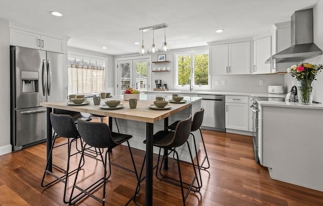 kitchen featuring wall chimney exhaust hood, appliances with stainless steel finishes, light countertops, white cabinets, and recessed lighting