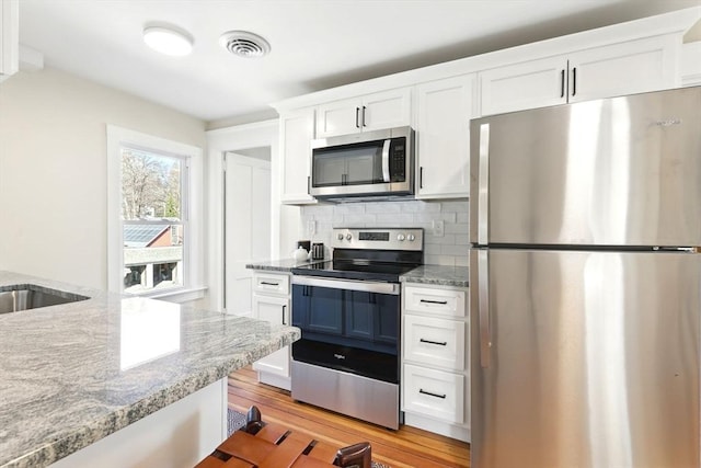 kitchen with visible vents, tasteful backsplash, appliances with stainless steel finishes, and white cabinetry