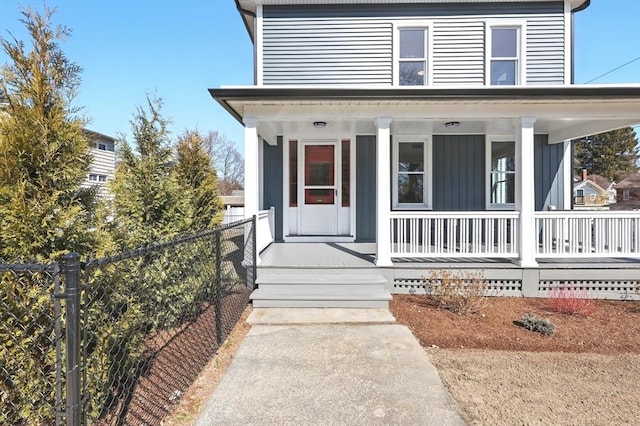 property entrance with board and batten siding, covered porch, and fence