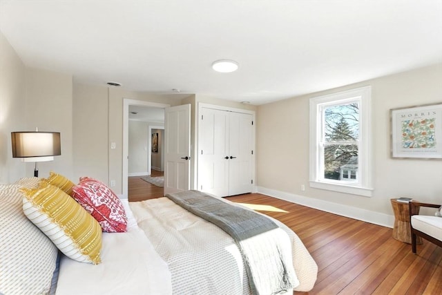 bedroom featuring a closet, baseboards, and hardwood / wood-style flooring