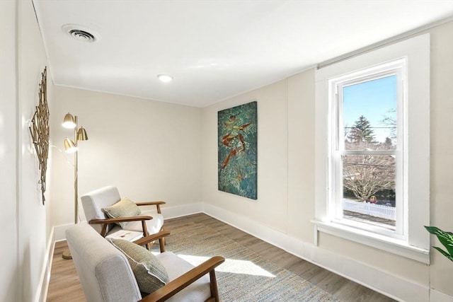 living area with visible vents, baseboards, and wood finished floors
