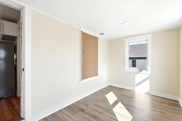 spare room with visible vents, baseboards, and wood finished floors