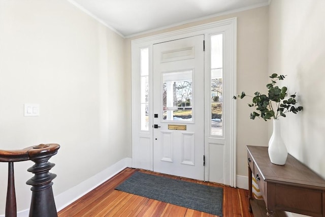entryway featuring baseboards, wood finished floors, and ornamental molding